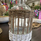 Clear glass bottle in woven rattan basket