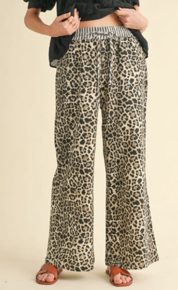 Leopard print pants with drawstring waistline features striped print, side pockets, and wide legs.